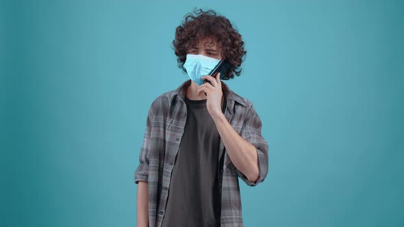 The Boy with Curly Charismatic Hair Talks on the Phone with the Mask on His Face and Moves in a Good