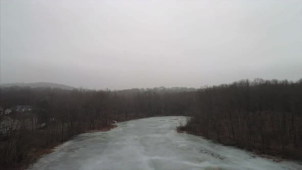 Flying Over a Frozen Lake Surrounded by Trees in Mahopac New York