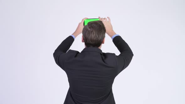Rear View of Young Businessman Taking Picture with Phone