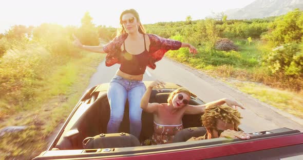 Beautiful brunette sitting on hood of convertible, yellow filter