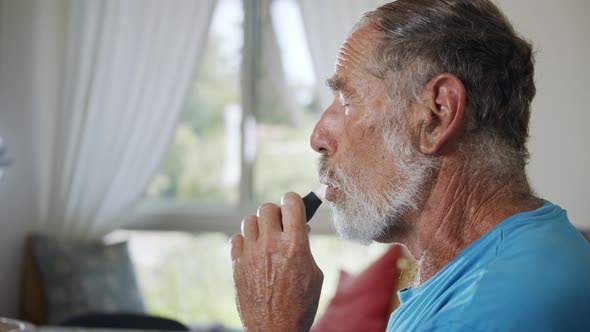 Man with Parkinson's disease using medical Cannabis in vaporizer to stop shaking