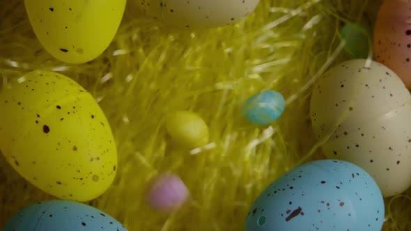 Rotating shot of Easter decorations and candy in colorful Easter grass 