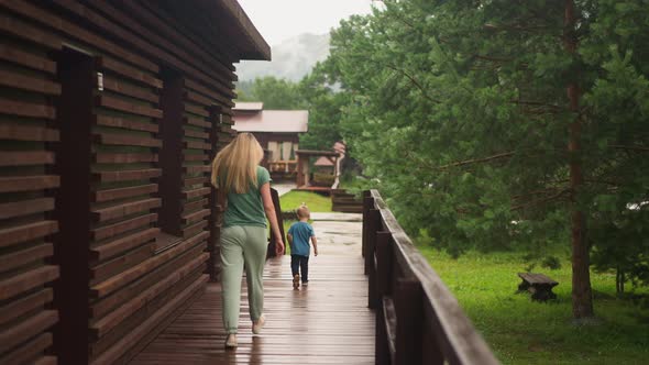 Woman Chases Funny Little Boy Running Along Wooden Veranda