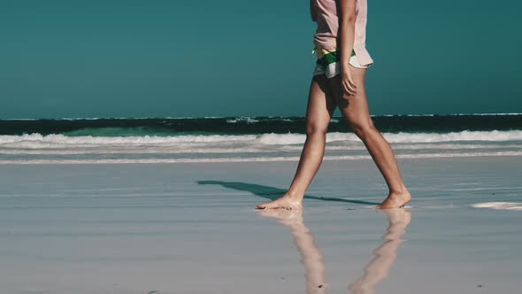 Legs of Young Woman Walking By White Sand Paradise Beach with Tidal Ocean Waves