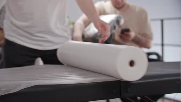 Tattooed Man Preparing the Place for His Work  Covering the Seat with Disposable Bed Sheet