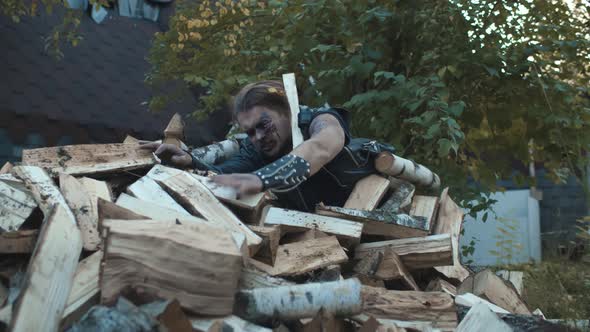 Portrait of Creepy Zombie Crawling Out of Pile of Firewood Outdoors