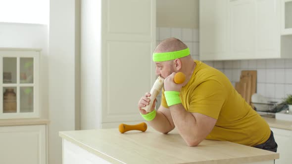 Fat Man Eating Shawarma Sitting at Table Doing Exercise for Hand with Dumbbell