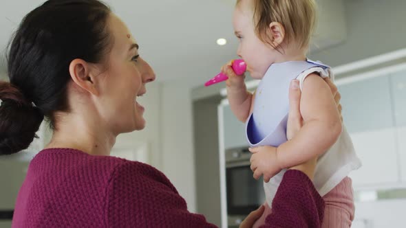 Caucasian mother holding her baby after feeding her at home