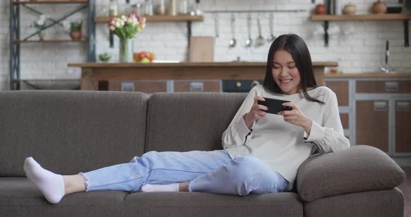 Young Asian Woman Pro Gamer Win the Game Playing Mobile Game on the Smartphone