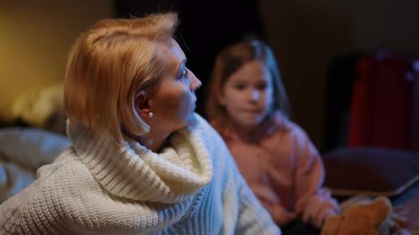 Anxious Mother Hugging Scared Daughter As Air Raid Alert Lamp Flashing at Background