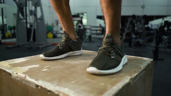 Feet of athlete jumping on cube in gym