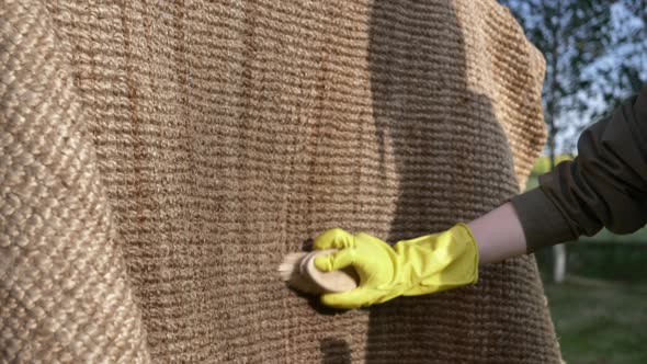 woman washing and cleaning with brush an eco-friendly jute rug in outdoor