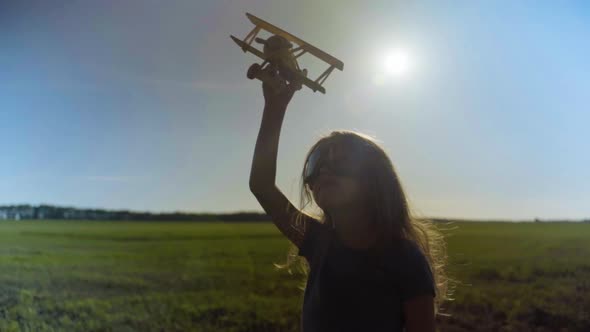 Little Girl Child In A Field With A Toy Plane At Sunset