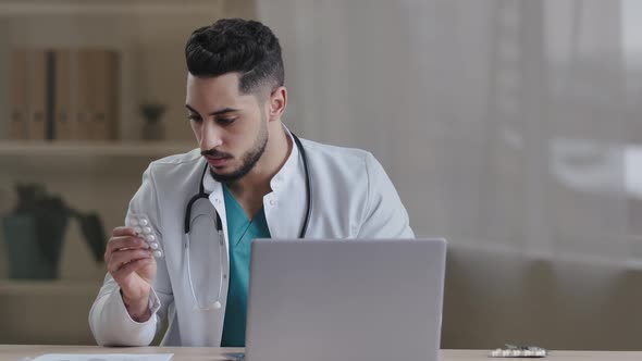 Young Arabian Male Doctor Nurse Professional Practitioner Work on Laptop Use Medical App Read Drug
