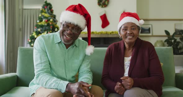 Happy african american senior couple in santa hats on video call at christmas time