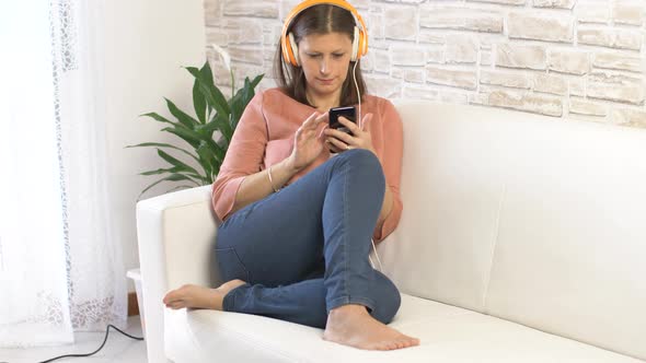 woman dressed in jeans dancing and listening music with headphones