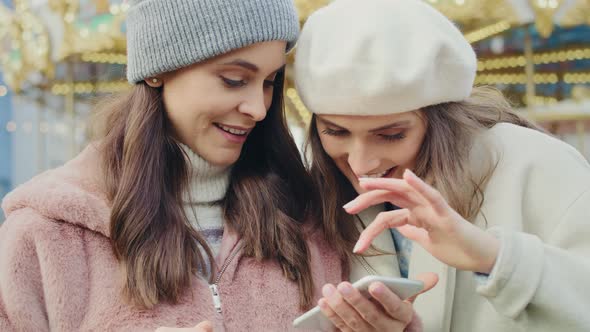 Video of two friends on a Christmas market browsing phone