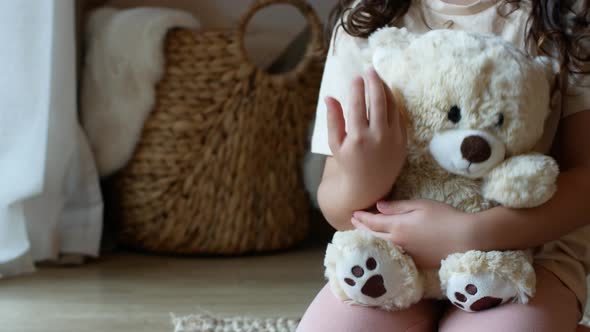 Child hugs and cuddles a cute beige teddy bear