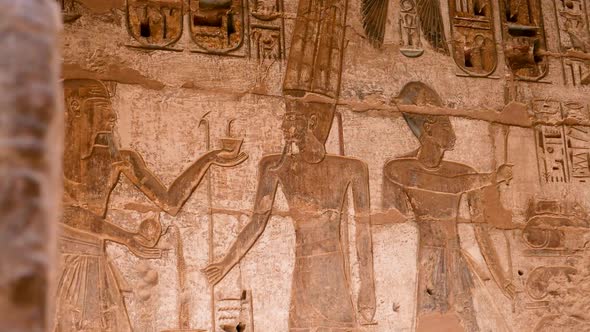 Detail of ancient Egyptian hieroglyphs of people and god on a wall, Habu Temple, Luxor, Egypt.