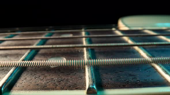 Slider Macro Shot of an Acoustic Guitar Neck with Metal Strings and Frets on Black Background