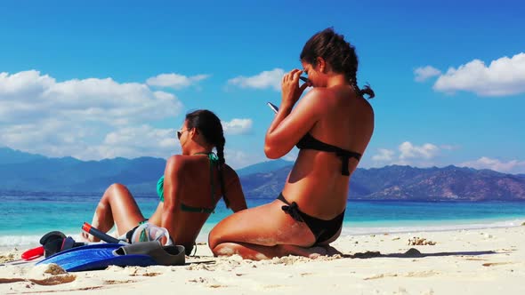 Tourists happy and smiling on perfect coastline beach vacation by blue water and clean sandy backgro