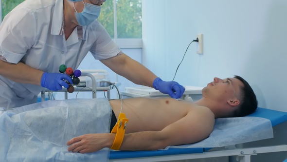 Nurse performing electrocardiography on a male patient