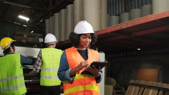 Female engineer worker quality control inspects by tablet at a paper factory.