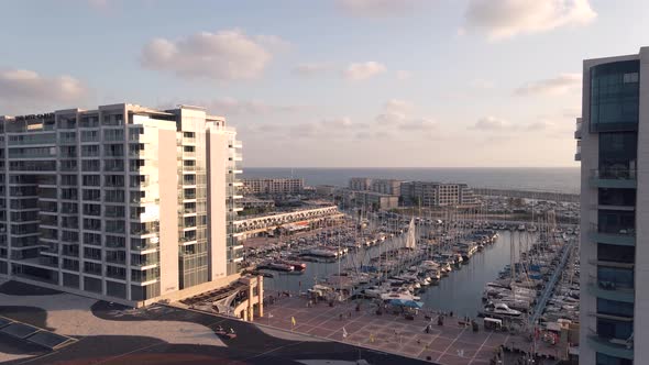 Aerial view of the harbor with boats and tall buildings in Herzelia in summer at sunset