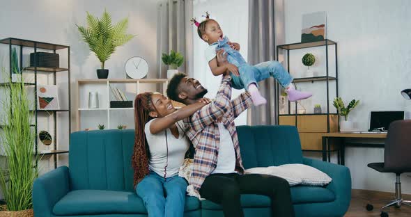 Cheerful African Parents Playing with Daughter at Home