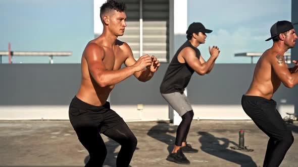 Group of diverse fit sports men doing side squat bodyweight workout training outdoors