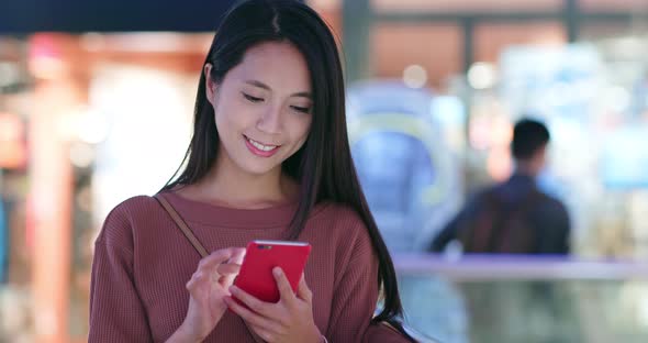 Woman check on the discount in mobile phone inside shopping plaza