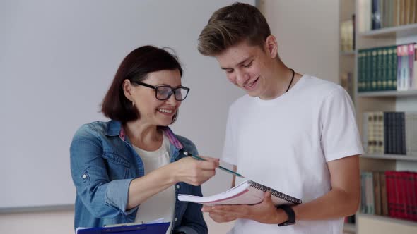 Back to College 17 Year Old Teen Boy Talking to Female Mentor Teacher Inside Class Library