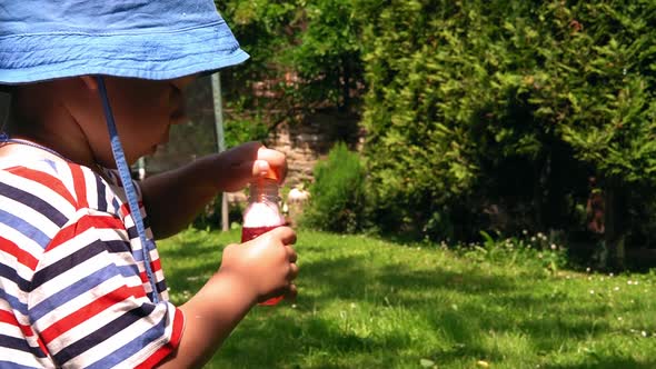 Close Up of Happy Cute Preschool Child Boy on Panama Blow Soap Bubbles on Hot Summer