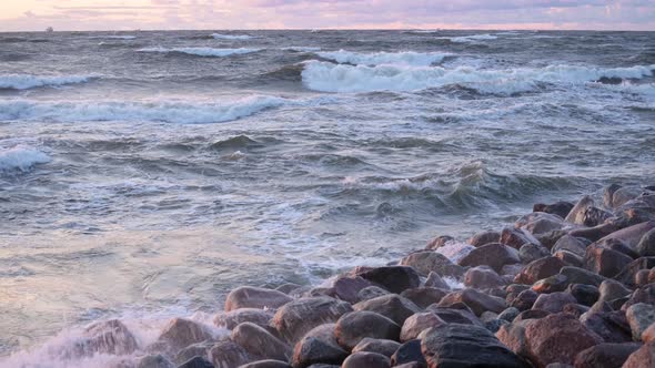 Sea water splash on a rock beach with beautiful sunset sky and clouds