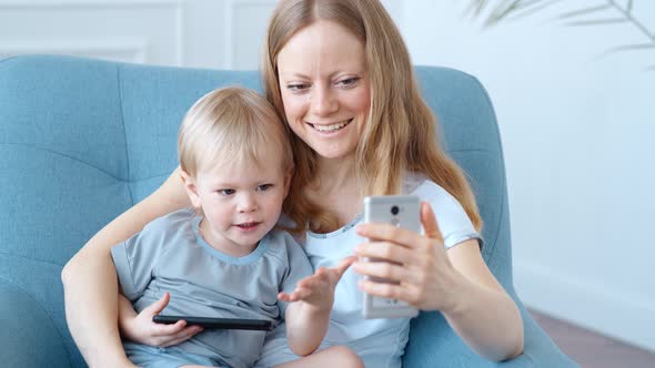 Young Mother and Son Are Enthusiastically Engaged in Online Entertainment on a Smartphone.