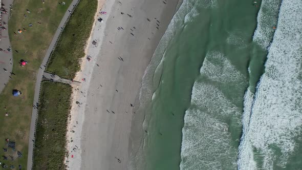 many tourists at Big Bay Beach during summer in Cape Town, top down aerial