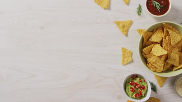 Video of tortilla chips, guacamole and salsa dip on a wooden surface