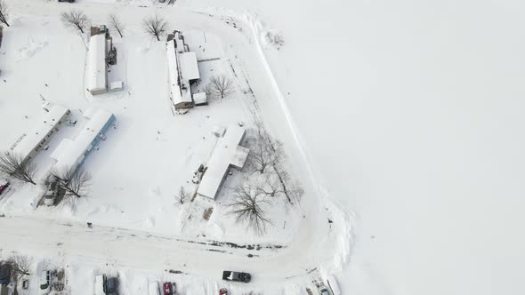 Top down view over snow covered mobile home park in winter. Plowed road encircling.