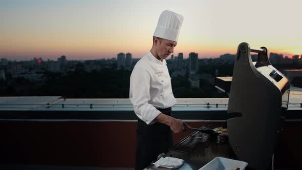 A professional Chef prepares a barbecue on the rooftop of a skyscraper. An expensive restaurant