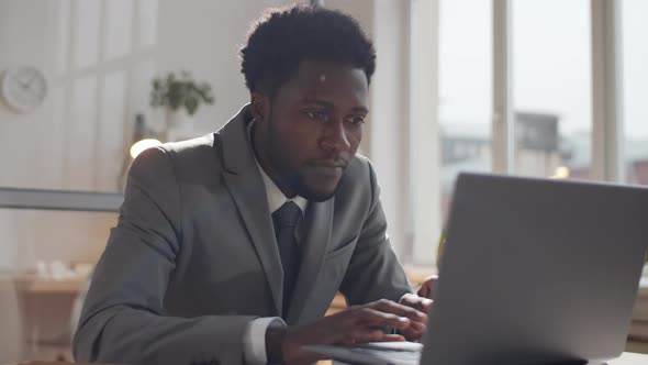 Afro-American Businessman Reading Good News on Laptop and Getting Excited