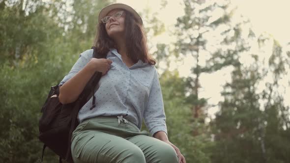 Woman Traveler Resting in the Forest. Portrait of a Young Woman Tourist in a Hat Outdoors