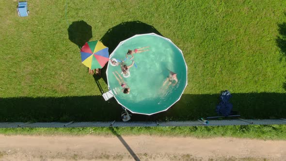 Aerial Shooting of Children Swimming in the Round Swimming Pool in the Backyard