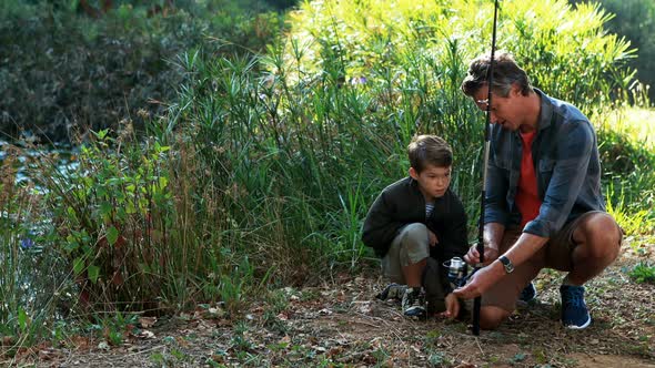 Father teaching son to use fishing rod in the park