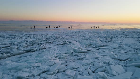 A drone flies over the ice hummocks to tourist group. Hovercrafts in background