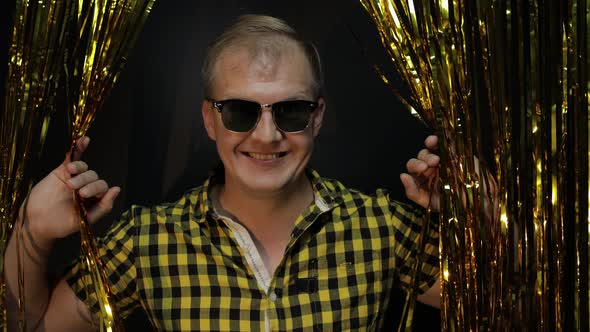 Portrait of Caucasian Man Posing on Black Background. Gold Shining Foil Strips. Party, Music, Disco