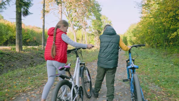 Children Walking in the Woods with Bicycles