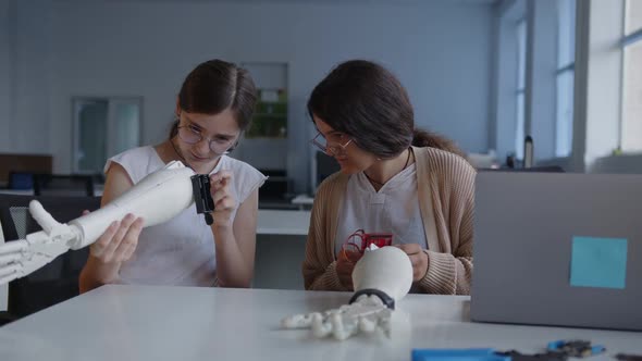 Girls Attentively Look on the 3D Printed Hands