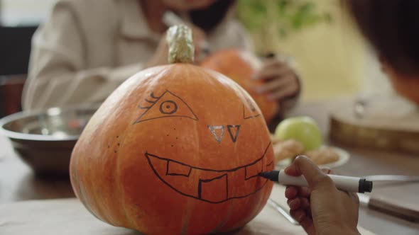 An Adult Lady is Finishing to Draw a Jack Face on a Halloween Pumpkin