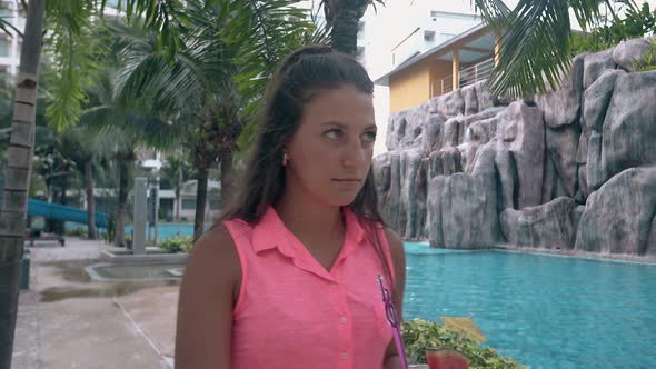 Woman Walks Around Hotel with Green Palms and Grey Stones