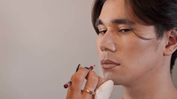 Makeup Studio - Makeup Artist Applying Red Lip Pencil Over the Lip Contour of Male Model